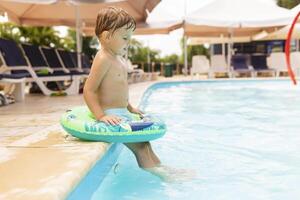 bambino nel nuoto piscina con gonfiabile cerchio gode estate vacanza foto