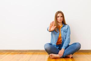 donna nel denim seduta su di legno pavimento mostrando fermare gesto foto