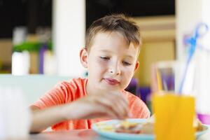 ragazzo mangiare prima colazione a un' colorato tavolo foto