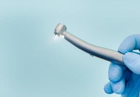 un' dentista indossare guanti nel il dentale ufficio detiene un' attrezzo prima Lavorando foto