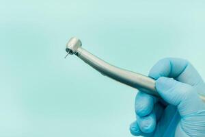 un' dentista indossare guanti nel il dentale ufficio detiene un' attrezzo prima Lavorando foto