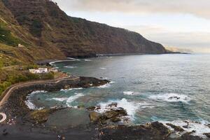 ruvido roccioso scogliere nel il nord di tenerife.black spiaggia nel il canarino isole. rocce, vulcanico rocce, atlantico oceano foto