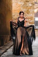 un' bellissimo elegante sposa nel un' nero vestito passeggiate attraverso Firenze, un' modello nel un' nero vestito nel il vecchio città di Italia foto