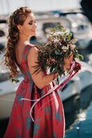 giovane modello ragazza nel un' bellissimo vestito con un' mazzo di fiori su il spiaggia nel Francia. ragazza con fiori nel primavera provence su il francese Riviera foto