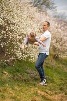 padre e figlia avendo un' divertimento insieme sotto un' fioritura albero nel primavera parco petrin nel praga, Europa foto