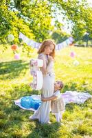 allegro madre e figlia avendo divertimento su bambino compleanno su coperta con carta decorazioni nel il parco foto