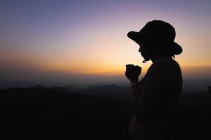 silhouette di un' donne è preghiere per Dio su il montagna. preghiere mani con fede nel religione e credenza nel Dio su benedizione sfondo. energia di speranza o amore e devozione. foto