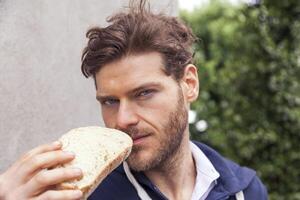 ritratto di bello uomo mentre mangiare un' fetta di pane foto