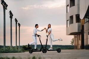 un' ragazza e un' tipo siamo a piedi su elettrico scooter in giro il città, un' coppia nel amore su scooter. foto