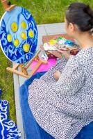 asiatico giovane donna pittura immagine di limoni su blu coperta nel casa terrazza. alto qualità foto