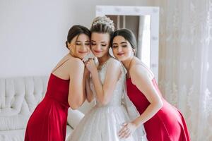 ritratto di il sposa con sua gli amici. elegante e elegante sposa con sua amici nel accoppiamento vestiti nel il camera nel il mattina. molti bellissimo ragazze nel uno foto. foto