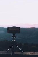 un' smartphone è registrazione il sole ambientazione al di sopra di un' montagna gamma. foto
