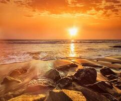 onde e rocce sulla spiaggia del tramonto foto