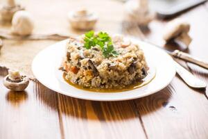 cucinato bulgur con funghi, carote e verdure nel un' piatto foto