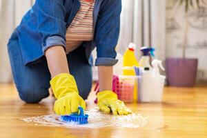donna nel gomma da cancellare guanti è utilizzando pavimento spazzola per pulizia pavimento foto