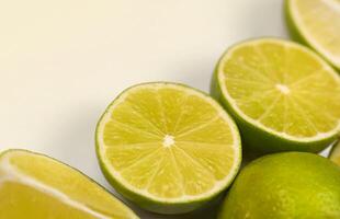 molti metà e fette di giallo Limone e verde lime su leggero bianca tavolo. fresco frutta su cucina di legno superiore foto