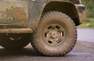 ruota avvicinamento nel un' campagna paesaggio con un' fango strada. fuori strada 4x4 suv automobile con ditry corpo dopo guidare nel fangoso strada foto