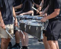 parecchi percussionisti di un' in marcia gruppo musicale tamburo linea riscaldamento su per un' parata foto