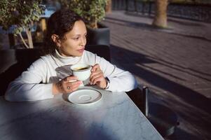 donna potabile caffè, godendo città vibrazioni a il lato cammina strada caffè foto