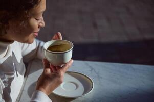 un' bianca porcellana tazza con caffè bevanda nel mani di un' sorridente donna telling fortune su caffè motivi. le persone. tempo libero foto