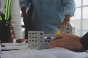 costruzione e struttura concetto di ingegnere o architetto incontro per progetto Lavorando con compagno e ingegneria utensili su modello edificio e planimetria nel Lavorando luogo, contrarre per tutti e due aziende. foto