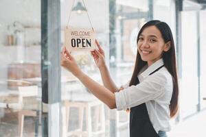 un' dedito bar proprietario si blocca un invitante benvenuto Aperto cartello, segnalazione il inizio di il giorno nel sua accogliente caffè negozio, un emblema di piccolo attività commerciale ospitalità e prontezza. foto