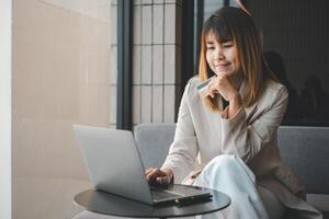 giovane donna in possesso di carta di credito e utilizzando il computer portatile. donna d'affari che lavora a casa. shopping online, e-commerce, internet banking, spendere soldi, lavorare da casa foto