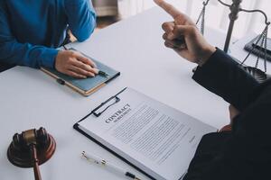 concetto di giustizia e diritto. il consulente legale presenta al cliente un contratto firmato con martelletto e diritto legale o una riunione del team legale presso uno studio legale in background foto