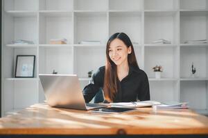 un' sorridente professionale donna è completamente impegnato con sua il computer portatile nel un' minimalista e luminosa ufficio spazio, riflettendo il moderno semplicità di di oggi opera ambiente. foto