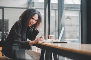 un' allegro donna d'affari gode un' spensierato momento mentre Lavorando su sua il computer portatile a un' bar, sua risata aggiungendo un' toccare di gioia per il professionale ambientazione. foto