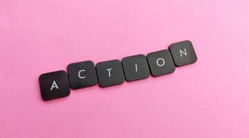 il parola azione farro su nel nero plastica pulsanti su un' rosa sfondo foto