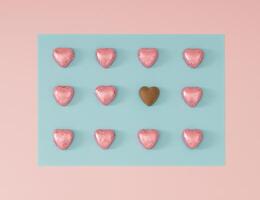 creativo romantico preparativi fatto con Foglio avvolto rosa cioccolato cuori su leggero pastello rosa e blu sfondo. minimo amore concetto. di moda cioccolato cuori idea. cioccolato estetico. piatto posizione. foto