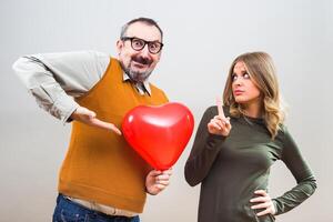 nerd uomo vuole per dare cuore forma Palloncino per un' bellissimo donna per mostrare sua il suo amore, ma lei è non interessato. foto