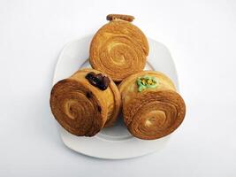 cromboloni, nuovo York rotolo brioche con un' varietà di salsa condimenti, servito su un' bianca piatto e isolato bianca sfondo. foto