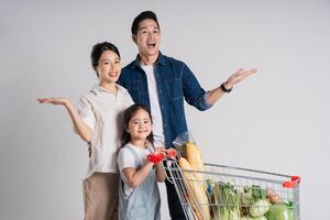 Immagine di asiatico famiglia spingendo un' supermercato carrello mentre acquisti, isolato su bianca sfondo foto