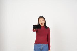giovane asiatico donna nel rosso maglietta Wow scioccato e mostrando smartphone vuoto schermo isolato su bianca sfondo foto