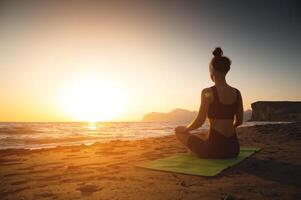 yoga donna Meditare a sereno tramonto o Alba su il spiaggia. il ragazza rilassa nel il loto posizione. dita piegato nel mudra. foto