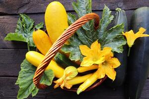 fresco zucchine nel un' cestino. zucchine con fiori su il vecchio rustico di legno tavolo foto