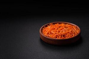 gustoso speziato coreano carota con spezie e erbe aromatiche su un' buio calcestruzzo sfondo foto