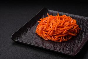 gustoso speziato coreano carota con spezie e erbe aromatiche su un' buio calcestruzzo sfondo foto