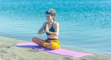 persona fare yoga esercizio su il spiaggia, persona rilassante su il spiaggia, personn fare yoga foto