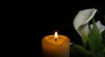 ardente cera candela e bianca calla giglio fiori nel buio foto
