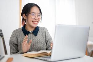 un' allegro giovane asiatico femmina Università alunno è studiando in linea nel un' bar co-working spazio. foto