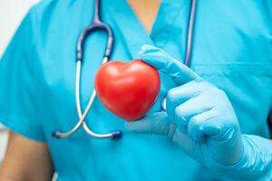 medico che tiene un cuore rosso nel reparto ospedaliero, concetto medico sano e forte. foto