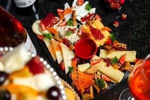 assortito formaggi e frutta piatto con un' bicchiere di vino foto