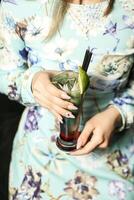 donna Tenere un' bevanda nel sua mano a un' spiaggia bar foto