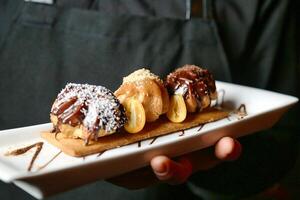 persona Tenere piatto con assortito pasticcini foto