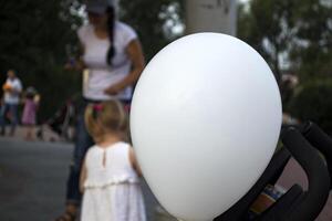 bianca Palloncino avvicinamento e bambini giocando nel il sfondo. foto