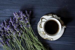 un' tazza di caffè, mazzo di lavanda e dolce su buio blu di legno tavolo. foto