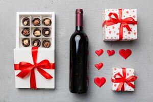 bottiglia di rosso vino su colorato sfondo per San Valentino giorno con regalo e cioccolato. cuore sagomato con regalo scatola di cioccolatini superiore Visualizza con copia spazio foto